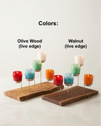 Two wooden candle holders with colorful candles on a white background, labeled 'Olive Wood' and 'Walnut'.