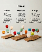 Three candle holders of different sizes with colorful glassybaby candles on a white background.