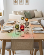 Dining table set with candles and a runner in a living room.